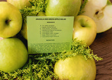 Load image into Gallery viewer, Apotheke Arugula and Green Apple salad ingredients on a green card with instructions. Green apples in the background surrounding the card.
